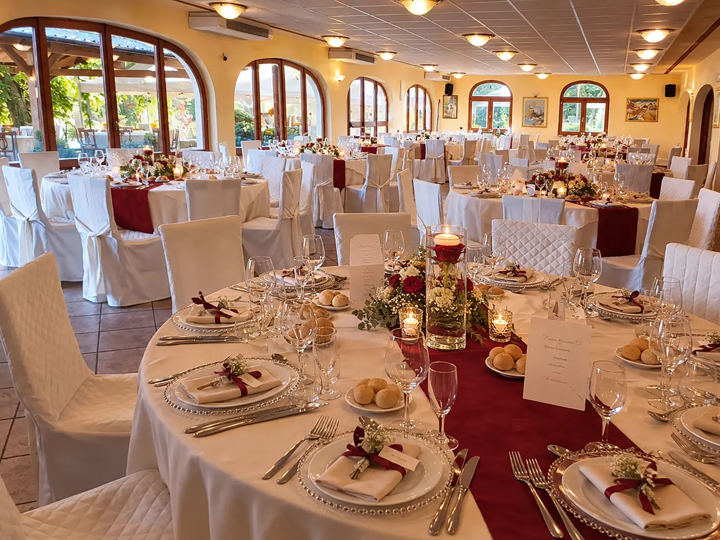 Allestimento della sala con tavoli, fiori e sedute bianche